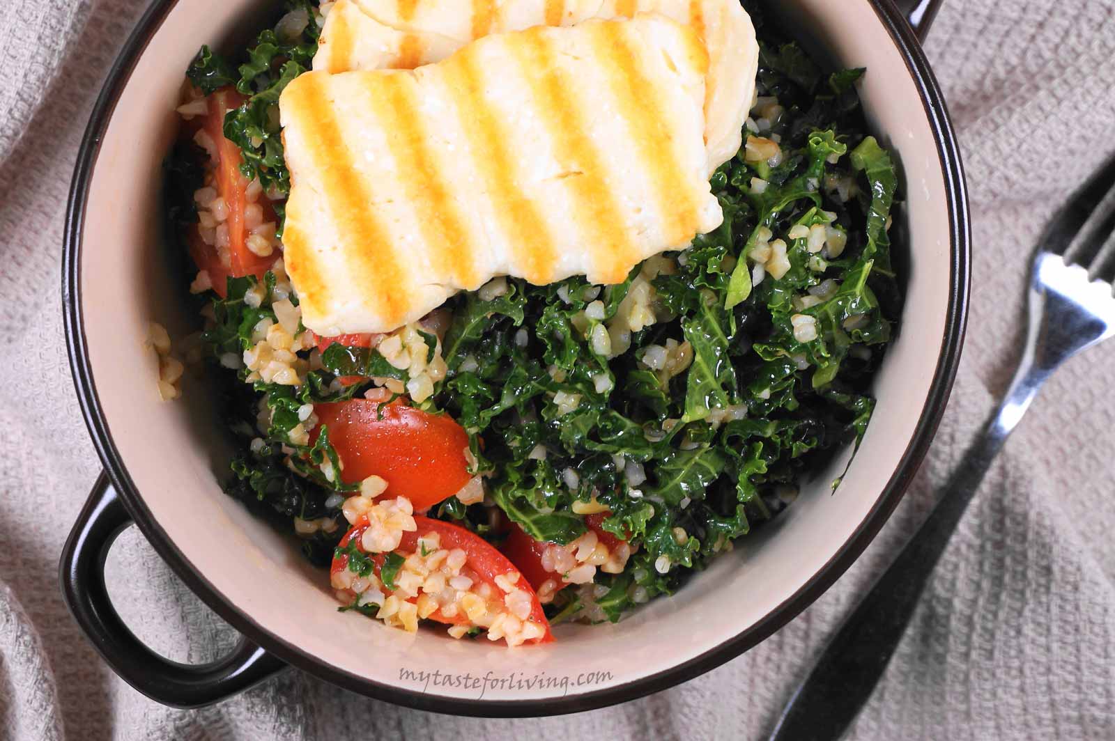 Nutritious salad prepared with kale, cherry tomatoes, red onions, bulgur and roasted halloumi.